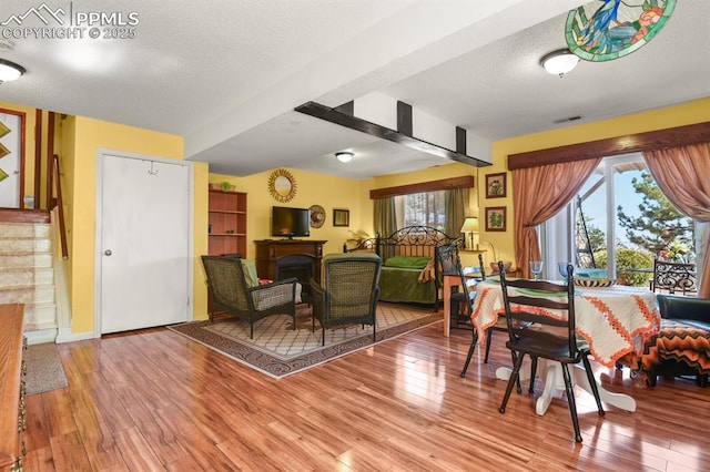 dining space with visible vents, a fireplace, wood finished floors, and stairs