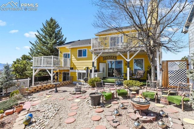 back of property featuring a patio, a balcony, fence, a wooden deck, and an outdoor fire pit