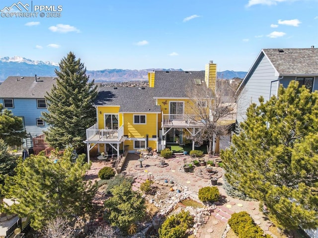 back of property featuring a patio area, a mountain view, a chimney, and stairs