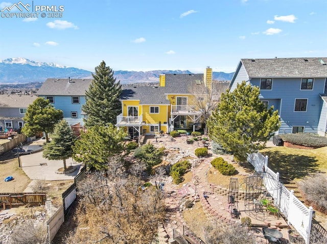 rear view of property featuring a residential view, a mountain view, and fence