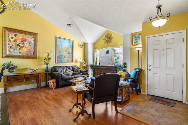 living room featuring lofted ceiling, wood finished floors, baseboards, and a textured ceiling