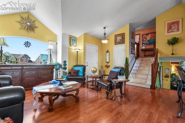 living room with a textured ceiling, wood finished floors, stairs, and vaulted ceiling