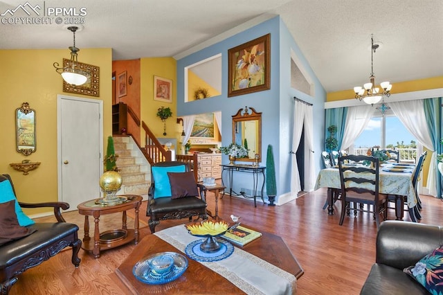 living room with a textured ceiling, wood finished floors, lofted ceiling, a chandelier, and stairs