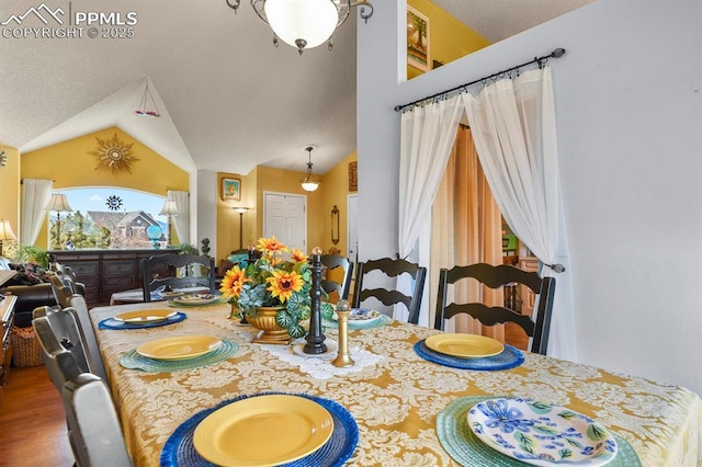 dining room with a textured ceiling, wood finished floors, and vaulted ceiling