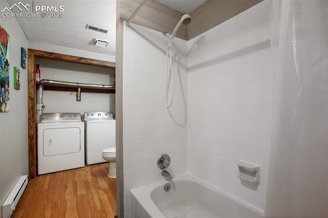 full bathroom featuring washing machine and clothes dryer, wood finished floors, toilet, baseboard heating, and shower / bathtub combination