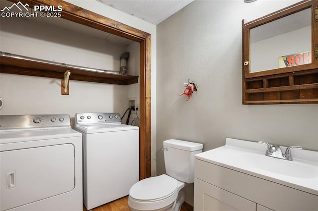 bathroom featuring separate washer and dryer, toilet, and a sink