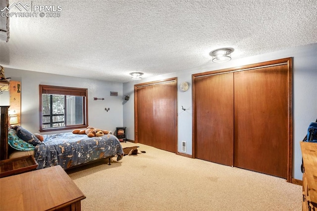 bedroom with carpet flooring, multiple closets, and a textured ceiling