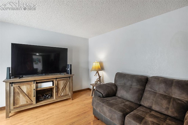 living room with baseboards, light wood-type flooring, and a textured ceiling