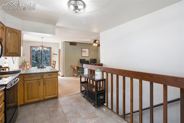 kitchen with decorative light fixtures, ceiling fan with notable chandelier, black range with electric cooktop, tile countertops, and brown cabinets