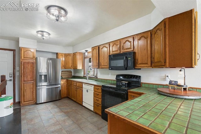 kitchen featuring a sink, brown cabinetry, tile counters, and black appliances