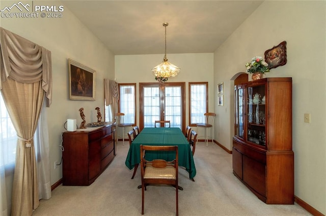 3012 S Electra Dr, Colorado Springs, CO 80906 - dining area featuring a chandelier, light colored carpet, and arched walkways