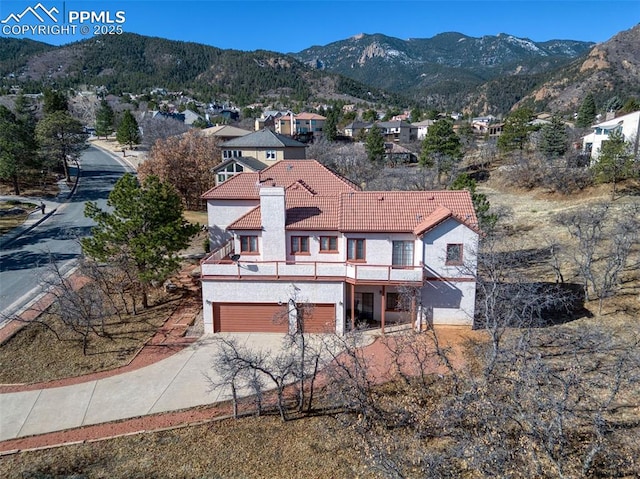 3012 S Electra Dr, Colorado Springs, CO 80906 - rear view of house with a tile roof, stucco siding, concrete driveway, and a mountain view