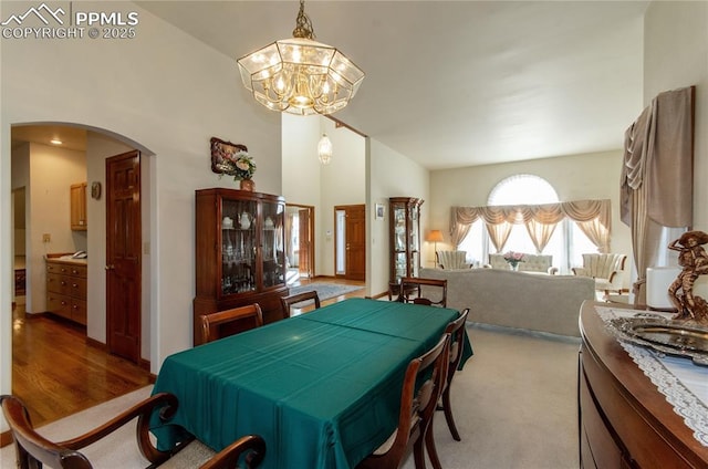 3012 S Electra Dr, Colorado Springs, CO 80906 - dining space featuring arched walkways, a chandelier, high vaulted ceiling, and light colored carpet