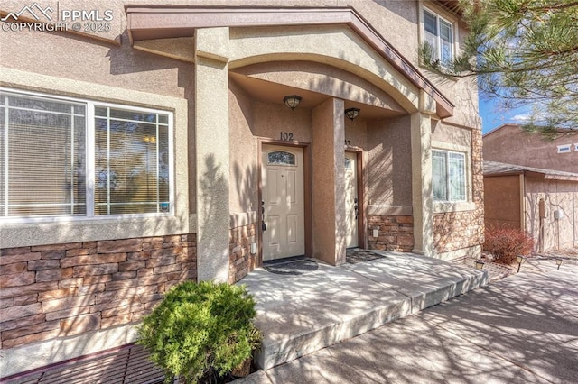 view of exterior entry with stucco siding and stone siding