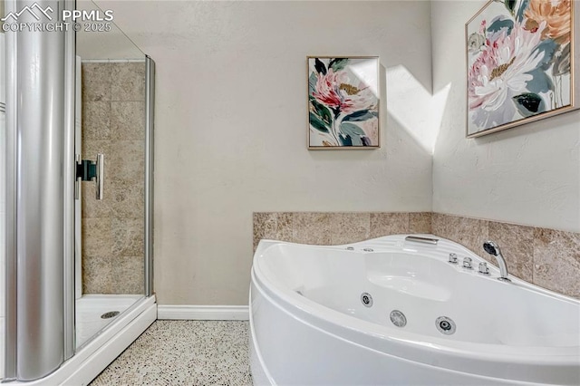 bathroom featuring a stall shower, a jetted tub, speckled floor, and baseboards