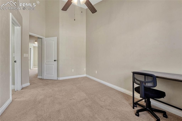 unfurnished office featuring a ceiling fan, a high ceiling, baseboards, and carpet floors