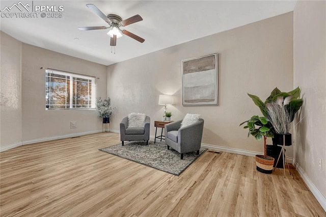 living area with a ceiling fan, wood finished floors, and baseboards