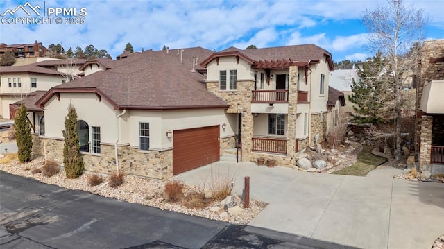 view of front of property featuring stucco siding, driveway, stone siding, an attached garage, and a balcony