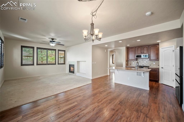 kitchen featuring visible vents, light countertops, a glass covered fireplace, stainless steel microwave, and open floor plan