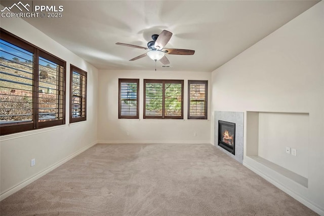 unfurnished living room with visible vents, a ceiling fan, a glass covered fireplace, carpet, and baseboards