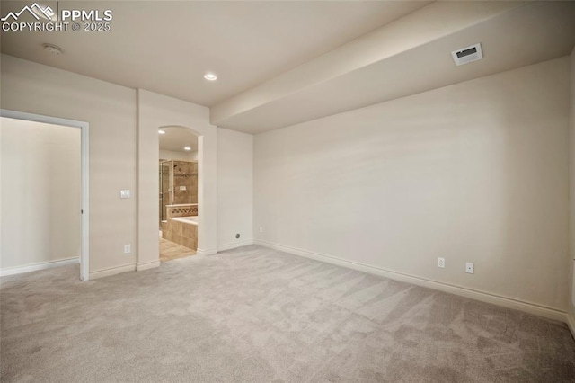 unfurnished bedroom with visible vents, arched walkways, carpet, and baseboards