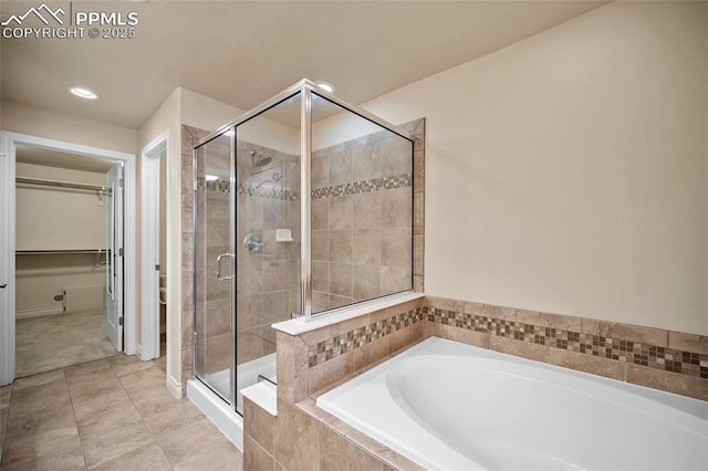 bathroom featuring a bath, tile patterned floors, a stall shower, and a walk in closet