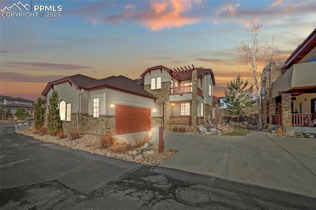 view of front of home featuring stucco siding, a garage, stone siding, driveway, and a pergola