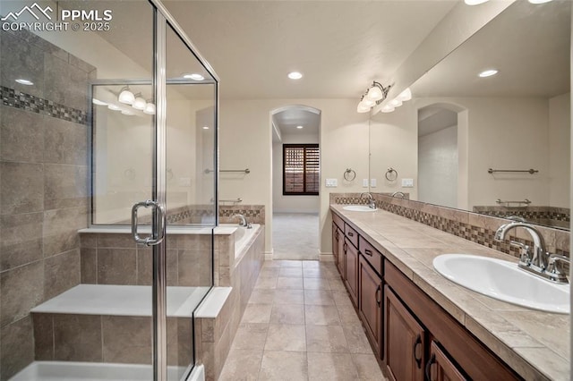 bathroom featuring a sink, a garden tub, a stall shower, and double vanity