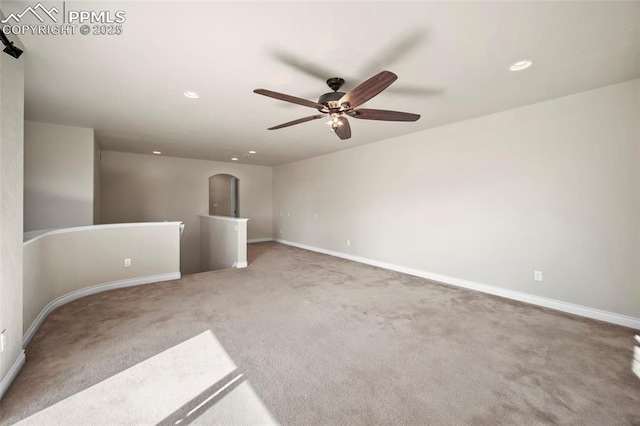 carpeted empty room featuring arched walkways, recessed lighting, baseboards, and ceiling fan