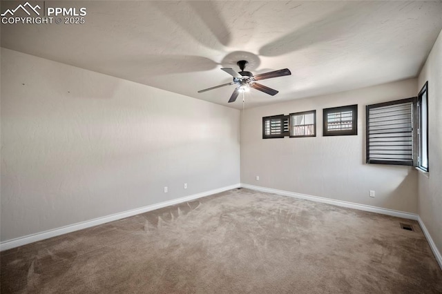 empty room with visible vents, baseboards, carpet, and a ceiling fan