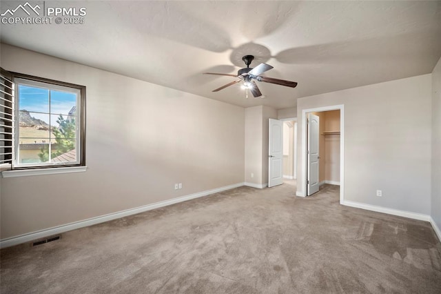 unfurnished bedroom featuring baseboards, a spacious closet, ceiling fan, and carpet flooring