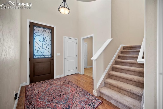 entrance foyer with baseboards, wood finished floors, and stairs