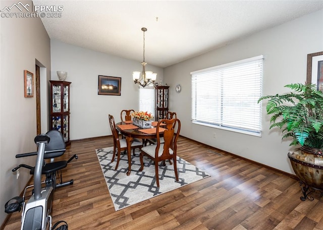 dining space featuring an inviting chandelier, wood finished floors, baseboards, and a textured ceiling