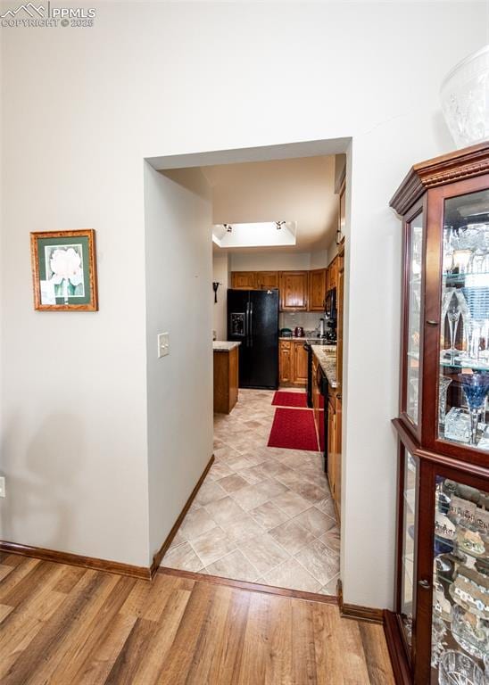 corridor with baseboards and light wood-style floors