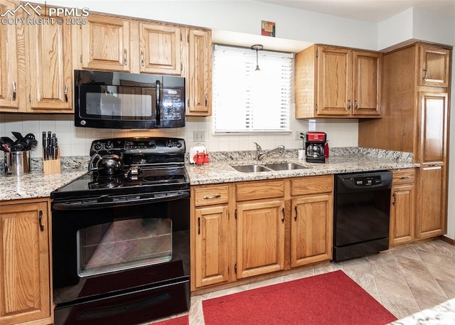 kitchen with a sink, decorative backsplash, light stone countertops, and black appliances