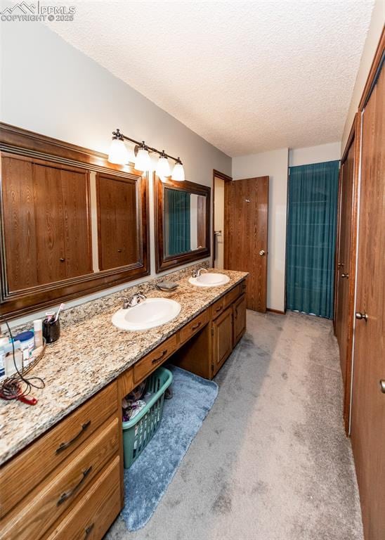 bathroom featuring a textured ceiling, double vanity, and a sink