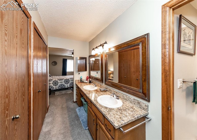 bathroom featuring double vanity, a textured ceiling, ensuite bathroom, and a sink