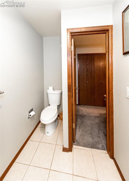 bathroom with baseboards, toilet, and tile patterned flooring