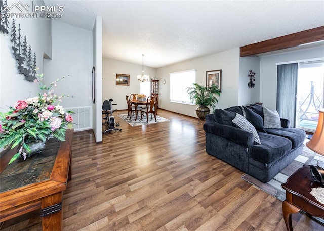 living area featuring visible vents, a textured ceiling, an inviting chandelier, and wood finished floors