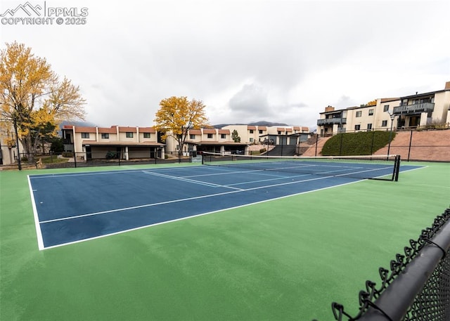 view of tennis court featuring a residential view and fence