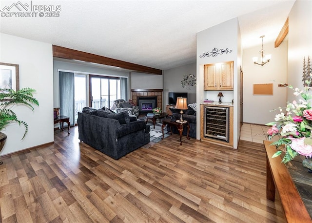 living room featuring lofted ceiling with beams, wine cooler, wood finished floors, and a tile fireplace