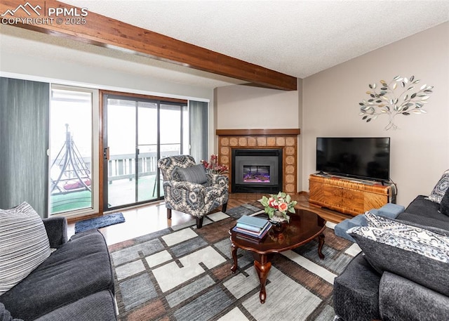 living area with beam ceiling, a fireplace, and a textured ceiling