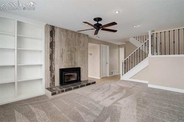 unfurnished living room with visible vents, a tiled fireplace, a textured ceiling, carpet, and stairs