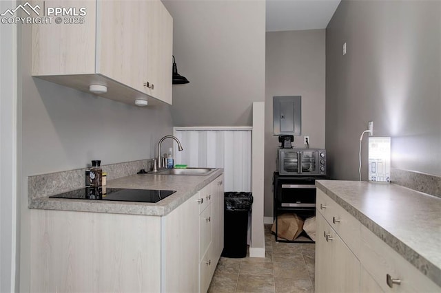 kitchen featuring electric panel, light countertops, black electric cooktop, and a sink