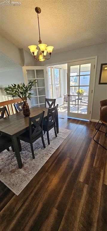 dining space with a textured ceiling, hardwood / wood-style flooring, baseboards, and a chandelier