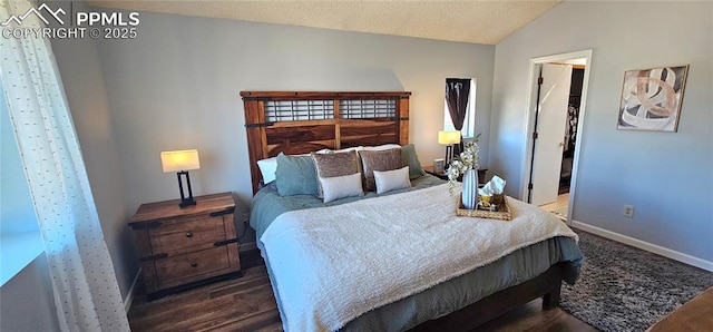 bedroom featuring a walk in closet, baseboards, vaulted ceiling, wood finished floors, and a textured ceiling