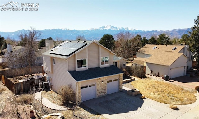 exterior space featuring fence, a mountain view, a garage, solar panels, and a chimney