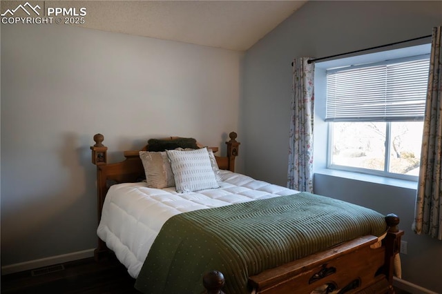 bedroom featuring visible vents, wood finished floors, baseboards, and vaulted ceiling