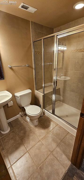 full bath featuring visible vents, toilet, a sink, a shower stall, and tile patterned flooring