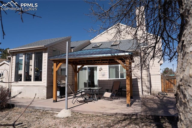 rear view of property featuring a gazebo, a patio, and fence